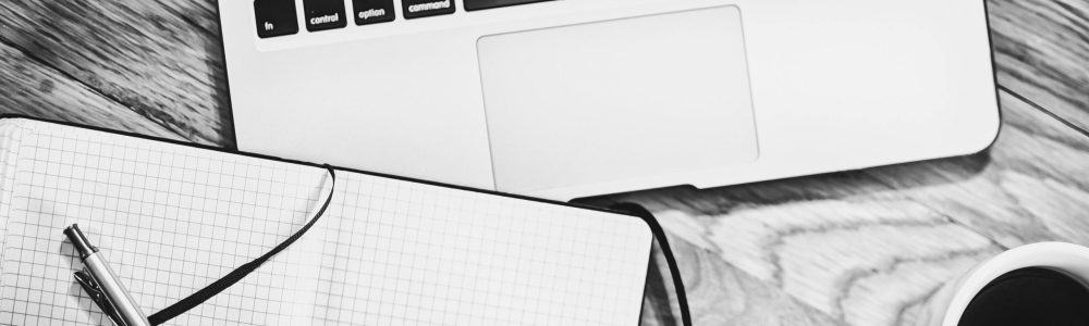 pexels-photo-265152-265152 Black and white image of a workspace featuring a laptop, notebook, pen, and coffee cup.